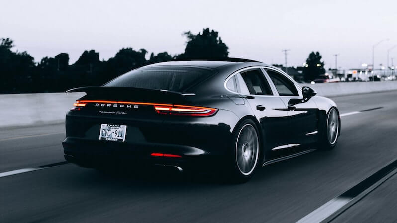 Image of a black Porsche driving down a road