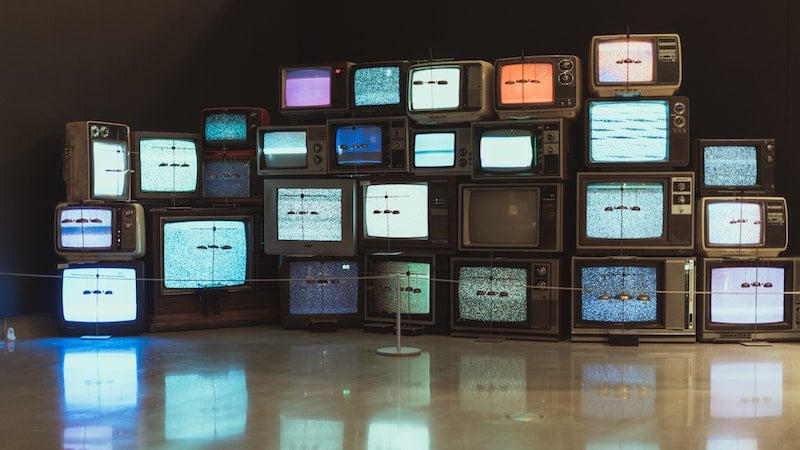 Vintage TVs stacked up on each other with their screens on 