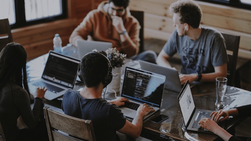 Group of men sat at laptops on a table