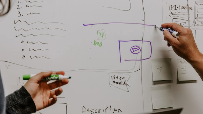 two people working collaboratively on a white board